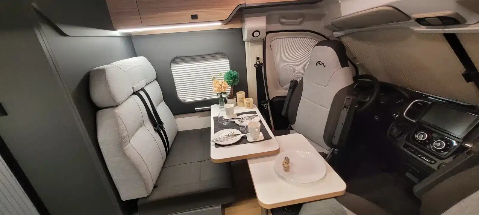 Innenansicht des MOOVEO VAN 54DB mit Sitzgruppe, Tisch und Fahrerkabine.