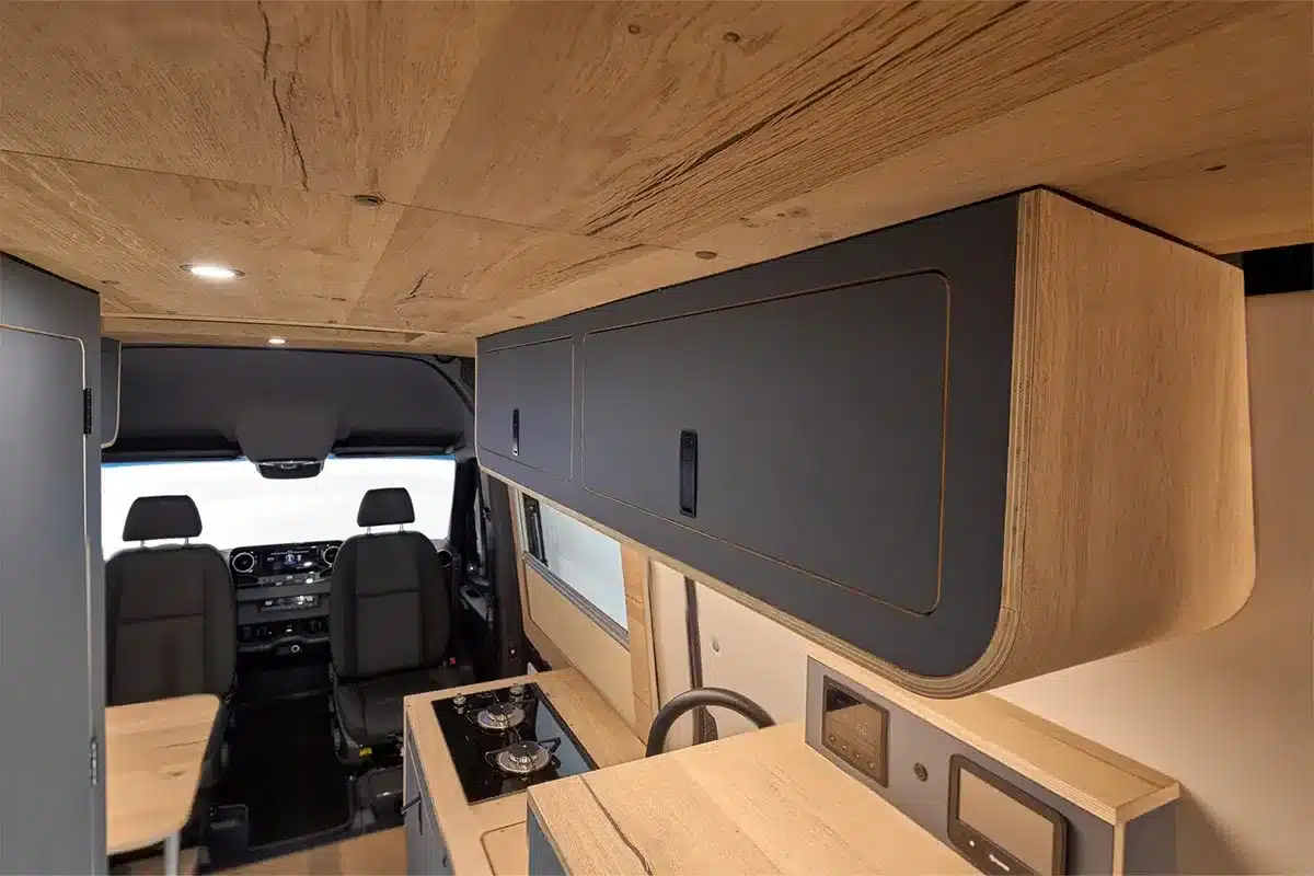 Innenansicht eines Morinter-Campers, ausgebauter Mercedes Sprinter mit Holzdekor und modernen Oberschränken
