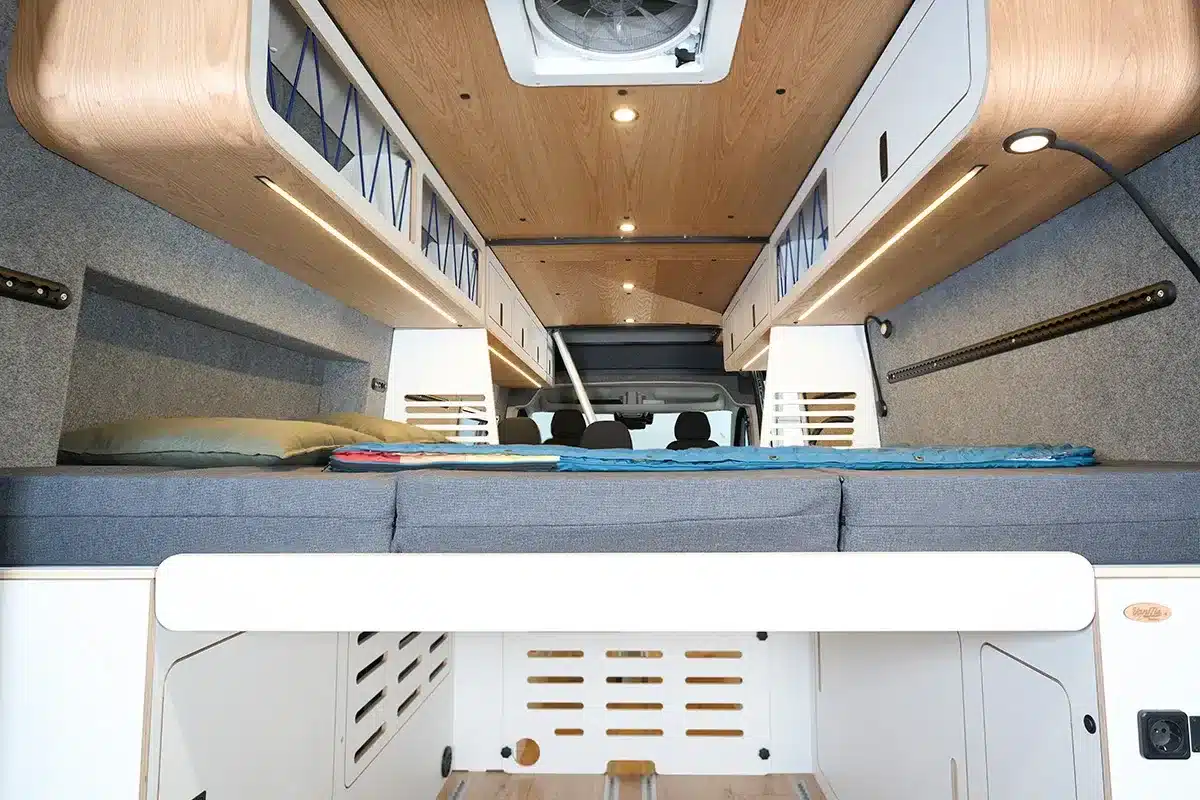 Blick auf das variable Heckbett und die modularen Möbel des Multi Racer Campervans