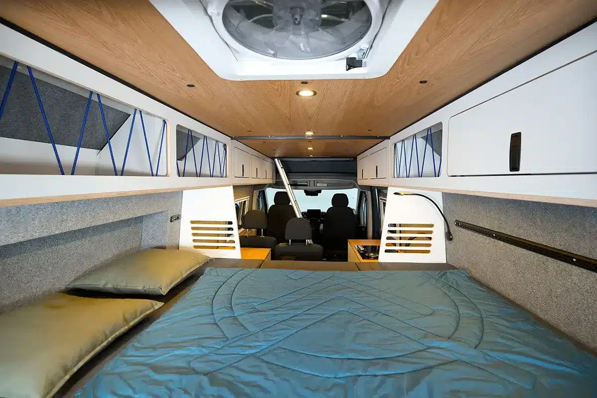 Blick auf das Heckbett, die Oberschränke und die variable Einrichtung im Multi Racer Campervan
