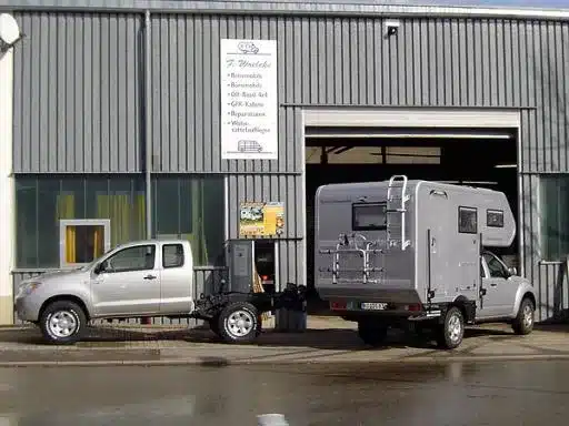 Nissan Navara Pickup mit abgesetzter GFK-Wohnkabine vor einer Werkstatthalle