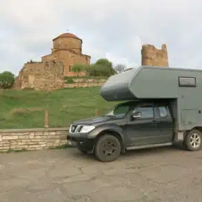 Absetzkabine auf Nissan Navara als Wohnmobil für Offroad und Vanlife, geparkt vor Ruine