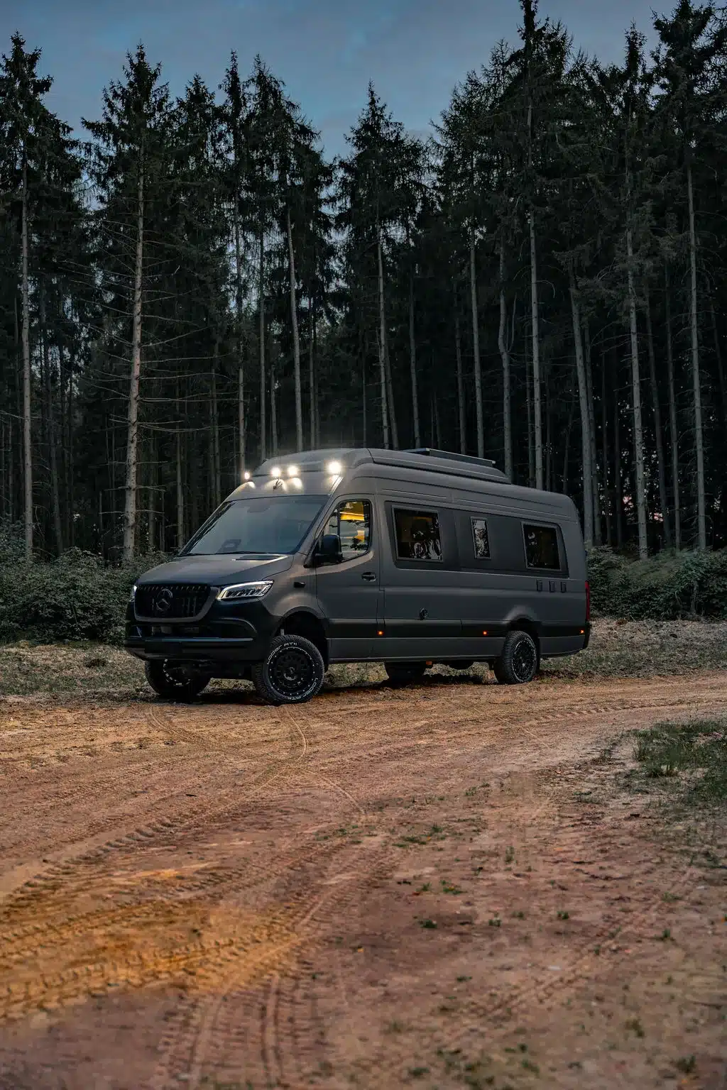 Der Noah Arche Campervan mit Hochdach und Zusatzbeleuchtung auf einem Waldweg.