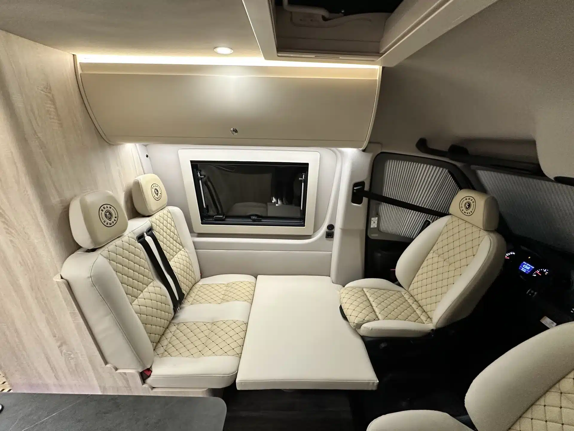 Hochwertig ausgestatteter Innenraum eines Campervans mit bequemer Sitzgruppe und modernem Design