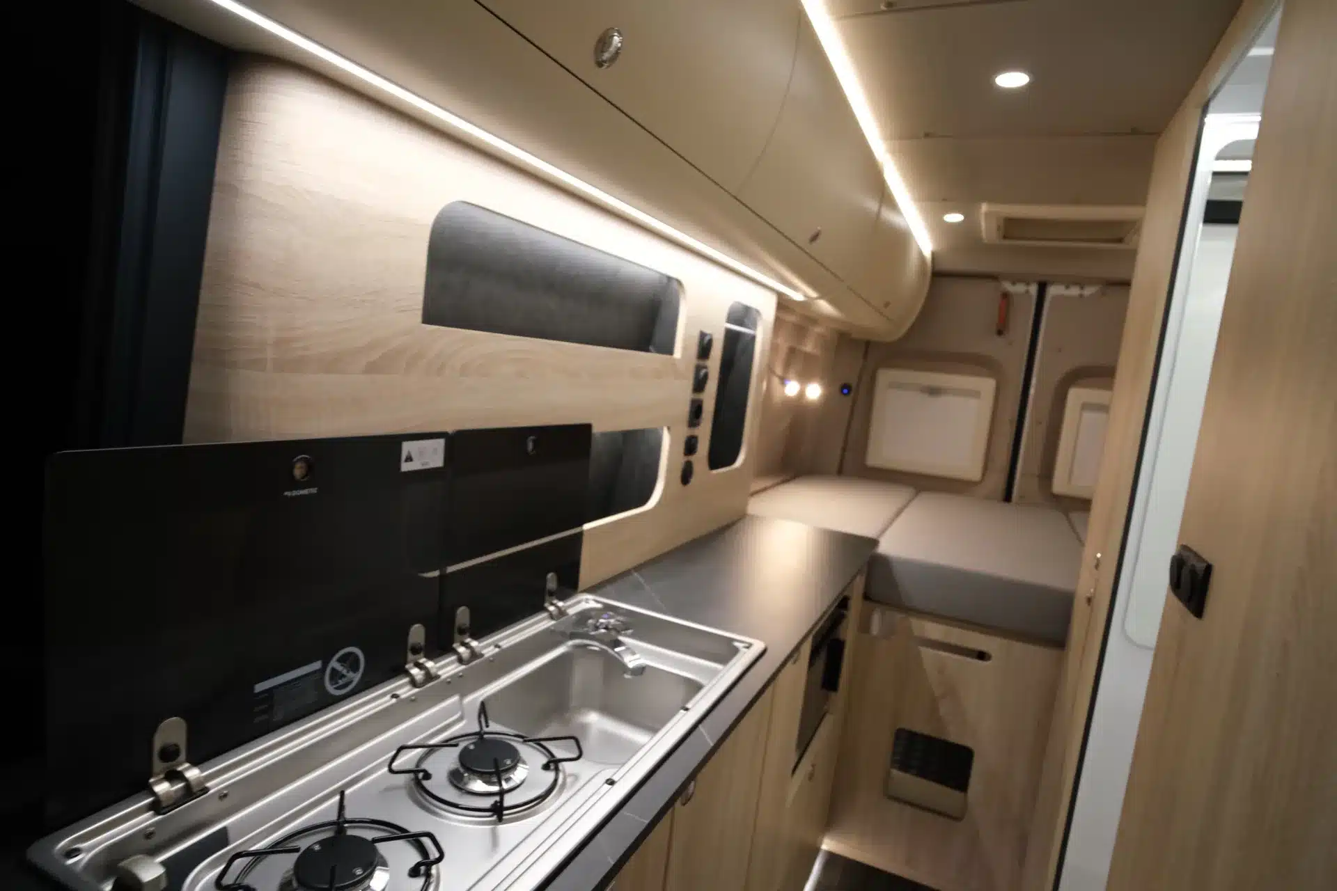 Innenansicht eines Campervans Noah Platin Line mit Küchenzeile, Doppelkocher, Spüle und Schlafbereich