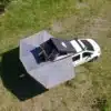Fahrzeug mit geöffneter OLC Adventure 360° Markise und Dachzelt auf einer Wiese von oben fotografiert.