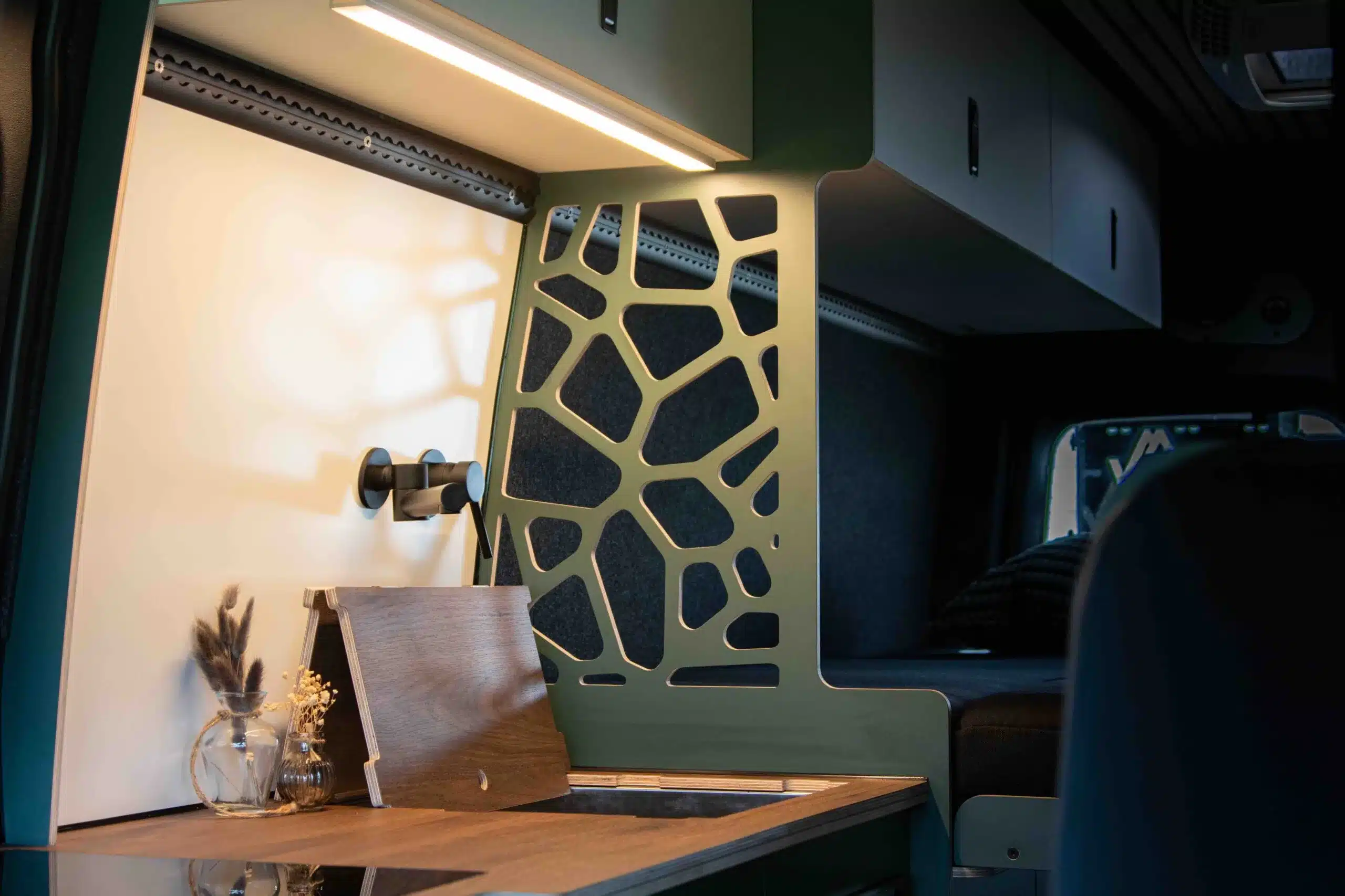 Detailansicht des modernen Innenausbaus vom SONIC MONSTER Campervan mit Trennwand, Holzoptik und Ablageflächen.