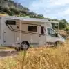 Benimar Tessoro T440 UP Reisemobil mit Markise, seitlich auf offenem Stellplatz in der Natur fotografiert.