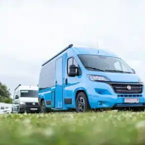 Blauer TS BusCamp TIPI Campingbus auf Basis des Fiat Ducato Serie 7, seitlich fotografiert auf einem Campingplatz.