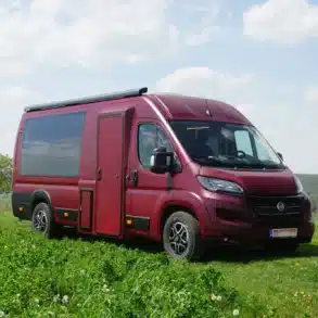 TIPI XL Campervan auf Basis des Fiat Ducato mit auffälliger Panoramaseitenscheibe auf einer Wiese