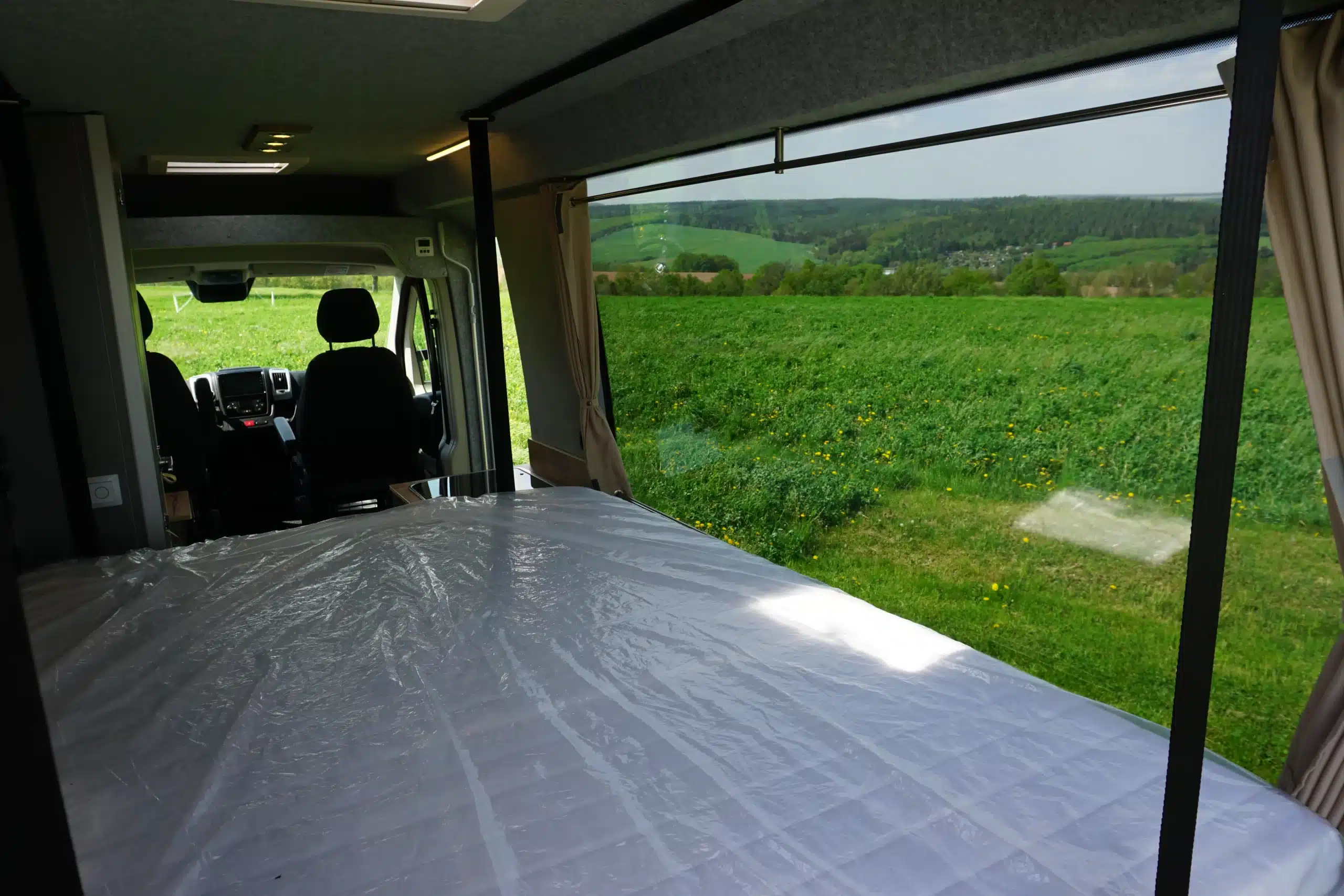 Innenansicht des TIPI XL Kastenwagens mit großem Panoramafenster und Bett