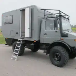 Unimog 435 Expeditionsmobil mit grauem Wohnaufbau, Leiter und Offroad-Bereifung