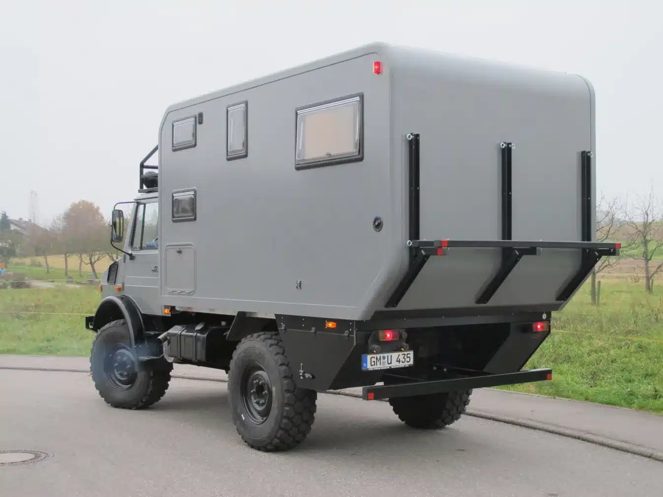 Unimog 435 Expeditionsmobil mit Wohnaufbau, fotografiert von hinten auf einer Straße