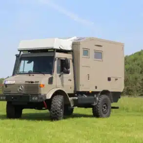 Unimog U1550L Expeditionsmobil mit Woelcke Wohnkabine und Dachzelt auf einer Wiese