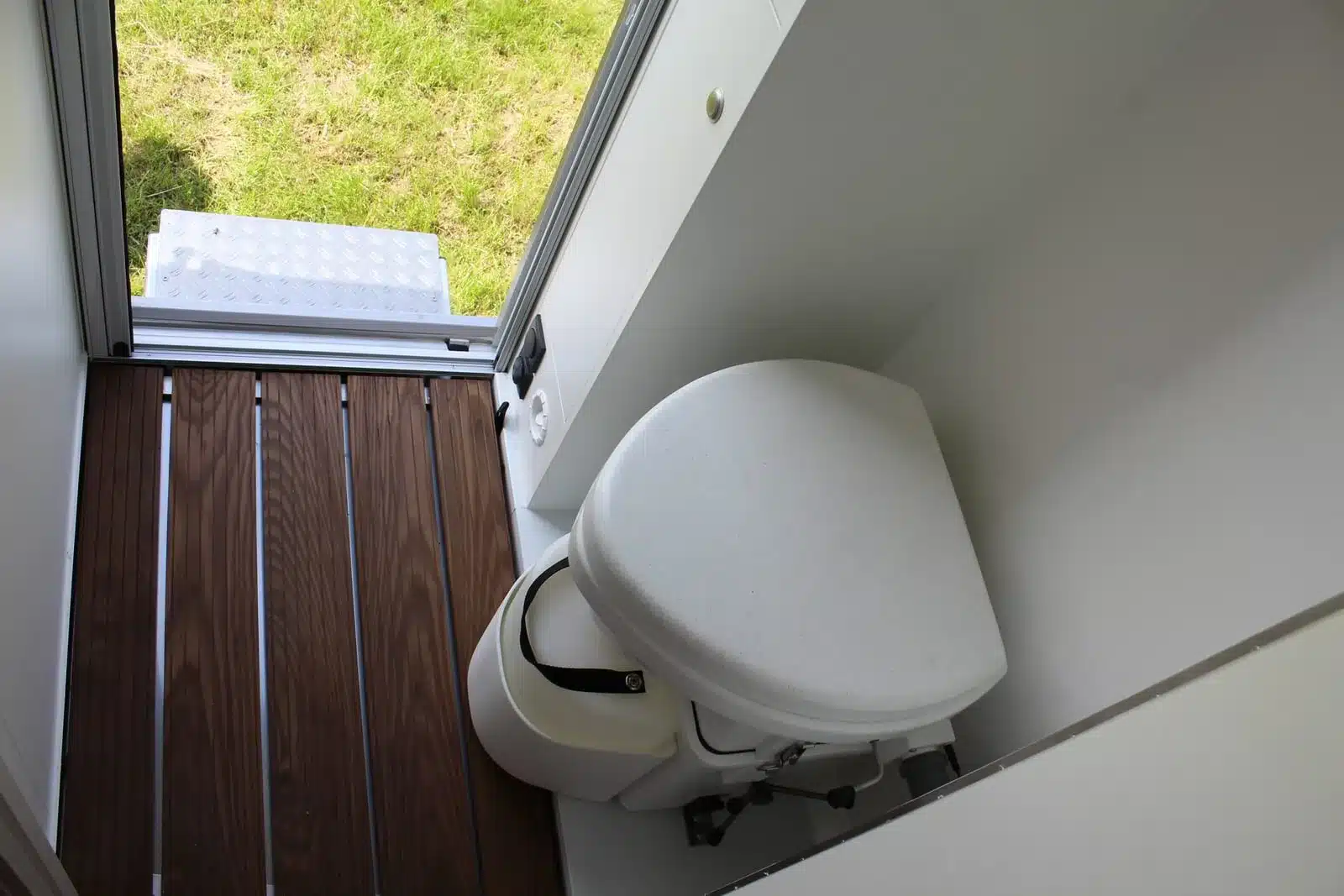 Toilette im Innenraum eines Unimog U1550L Expeditionsmobils mit Holzfussboden und Blick nach draußen