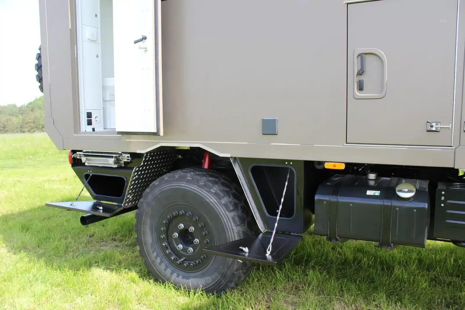 Seitliche Nahaufnahme eines Unimog U1550L mit Woelcke Wohnaufbau, geöffnete Tür und Trittstufe sichtbar