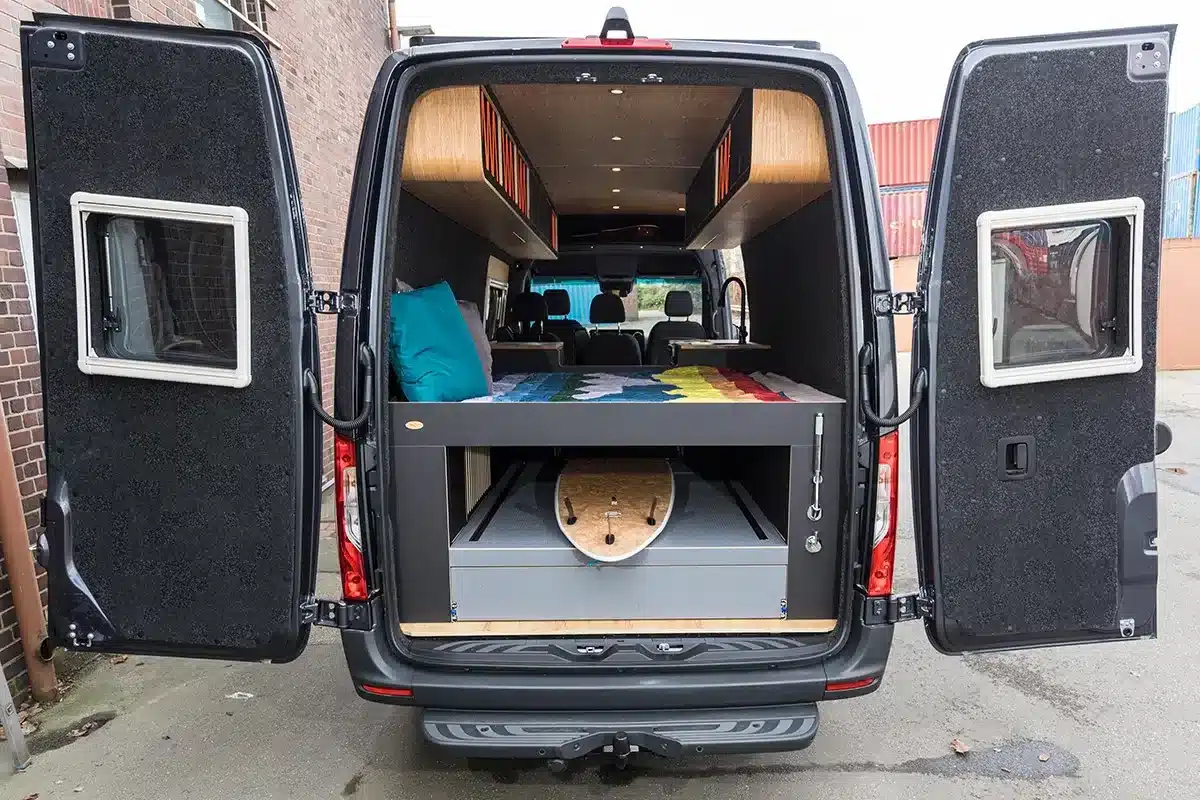 Blick in den geöffneten Heckbereich des Van in Black Campervans mit großer Heckgarage, Stauraum und Bettkonstruktion