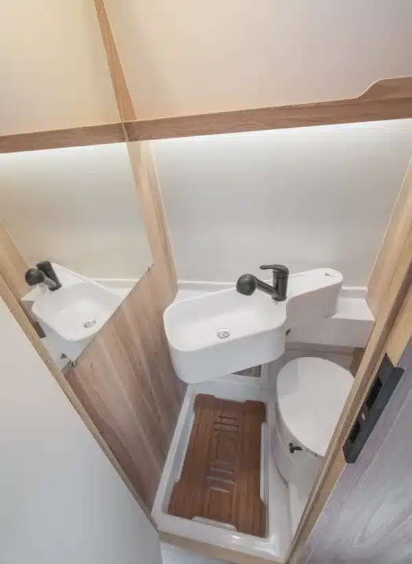Blick auf das Badezimmer mit Waschbecken, Wasserhahn, Spiegel und Toilette im VIICA 60 S Kastenwagen