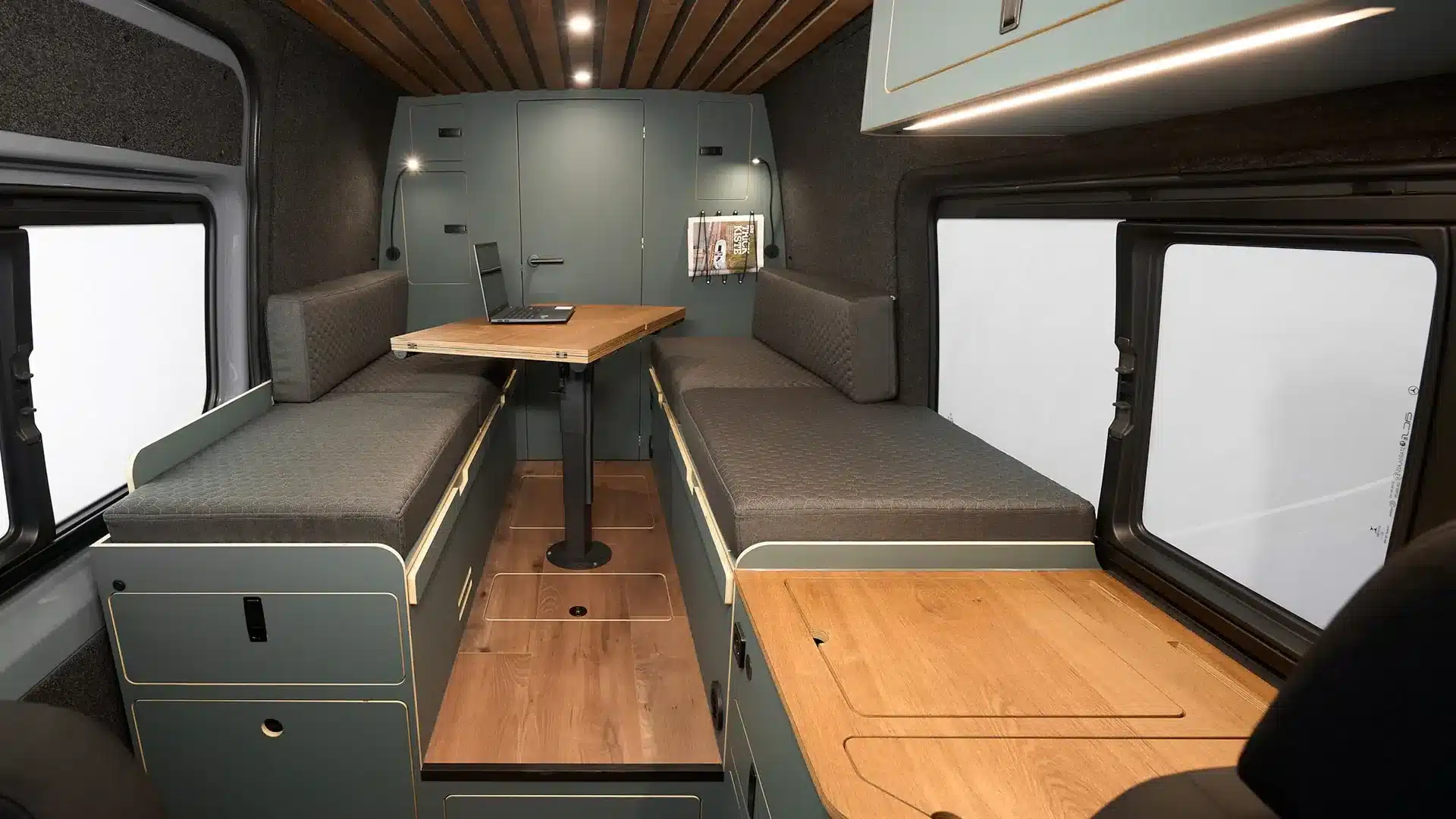 Innenansicht eines Mercedes Sprinter Campervans Wandertaube mit zwei Sitzbänken, Tisch und funktionalem Ausbau