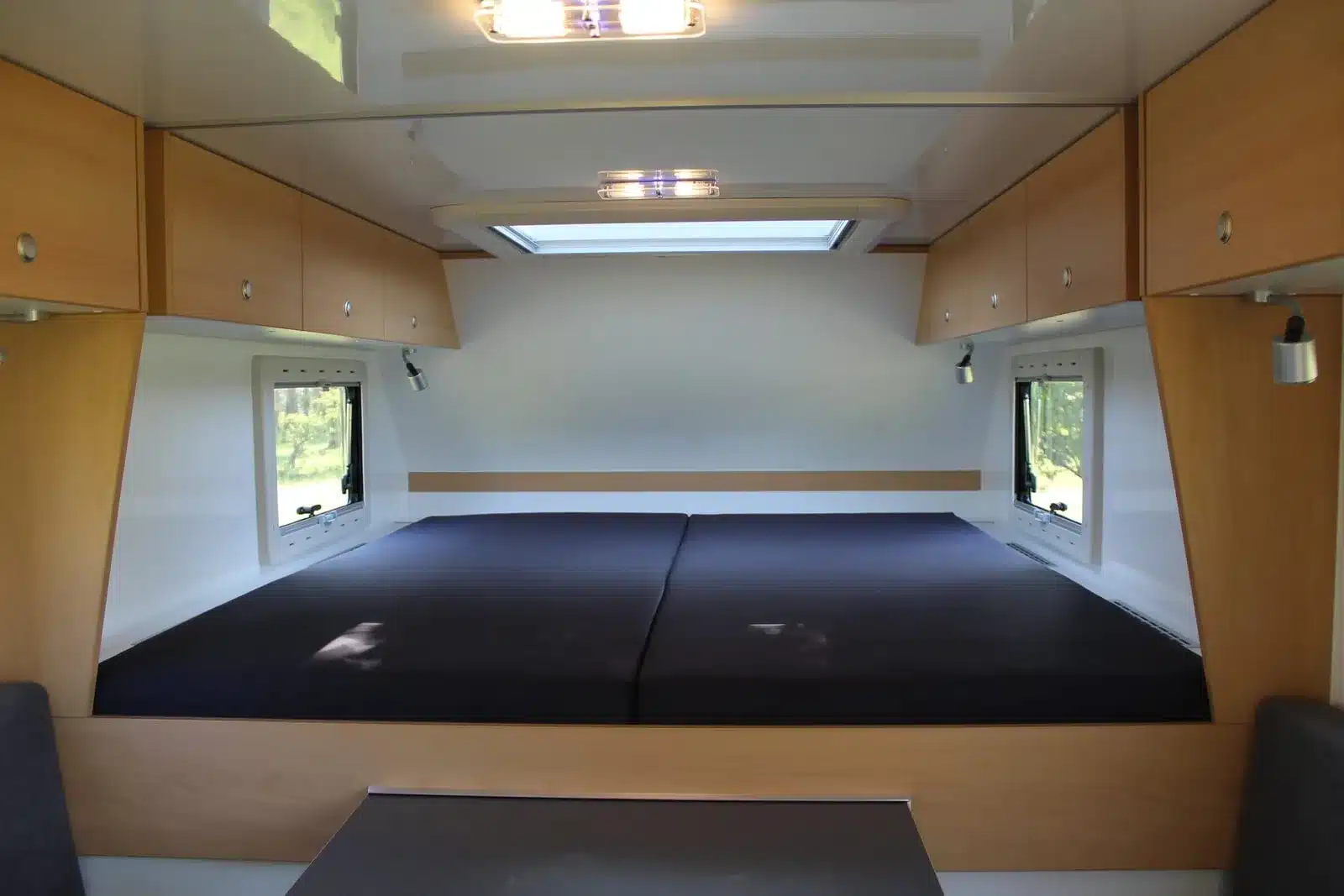Innenansicht des Alkoven-Schlafplatzes mit Doppelbett, Dachfenster und Stauraum im Woelcke Autark Amarok 2019
