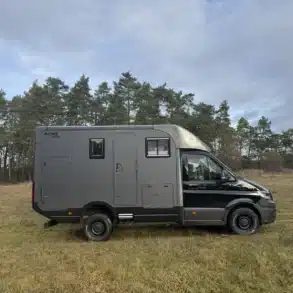 Woelcke Autark Crafter C11 als schwarzer Allrad-Camper auf einer Wiese