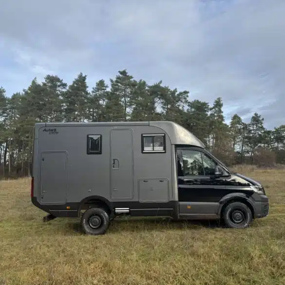 Woelcke Autark Crafter C11 als schwarzer Allrad-Camper auf einer Wiese