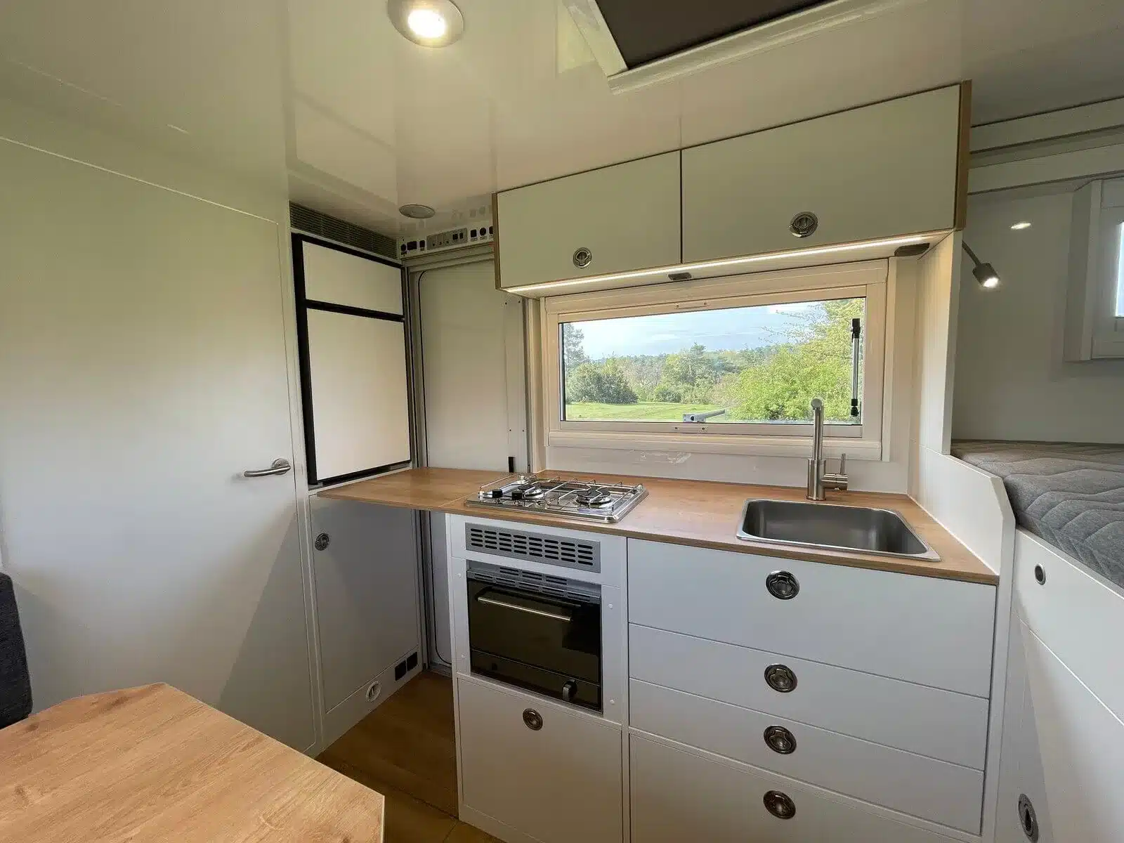 Küchenbereich mit Spüle, Kochfeld, Schränken und Fenster im Woelcke Autark Crafter C6 2023.