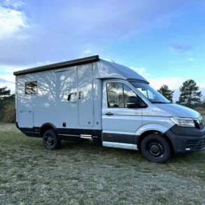 Woelcke Autark MAN TGE C9 Allradwohnmobil geparkt auf einer Wiese unter blauem Himmel