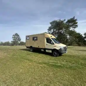 Beiges Allradwohnmobil Woelcke Autark Runner auf einer Wiese
