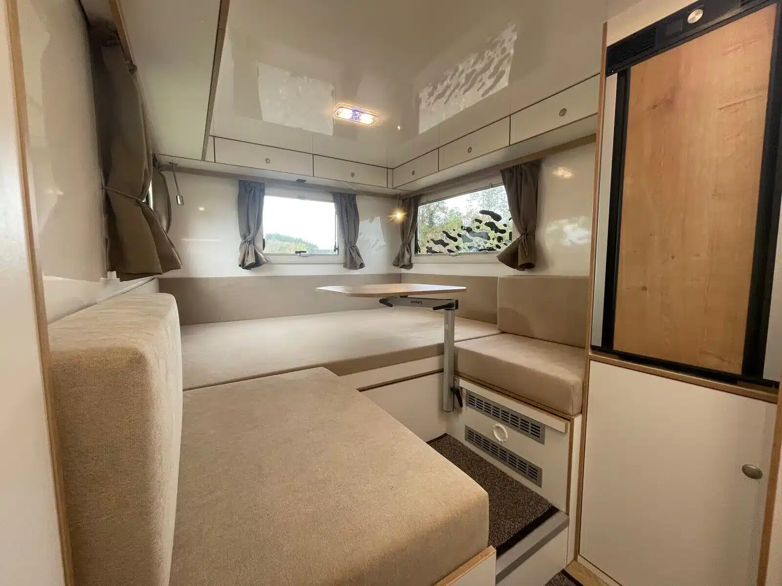 Moderner Sitzbereich mit Tisch und Kühlschrank im Woelcke Autark runner R4 Allrad-Camper