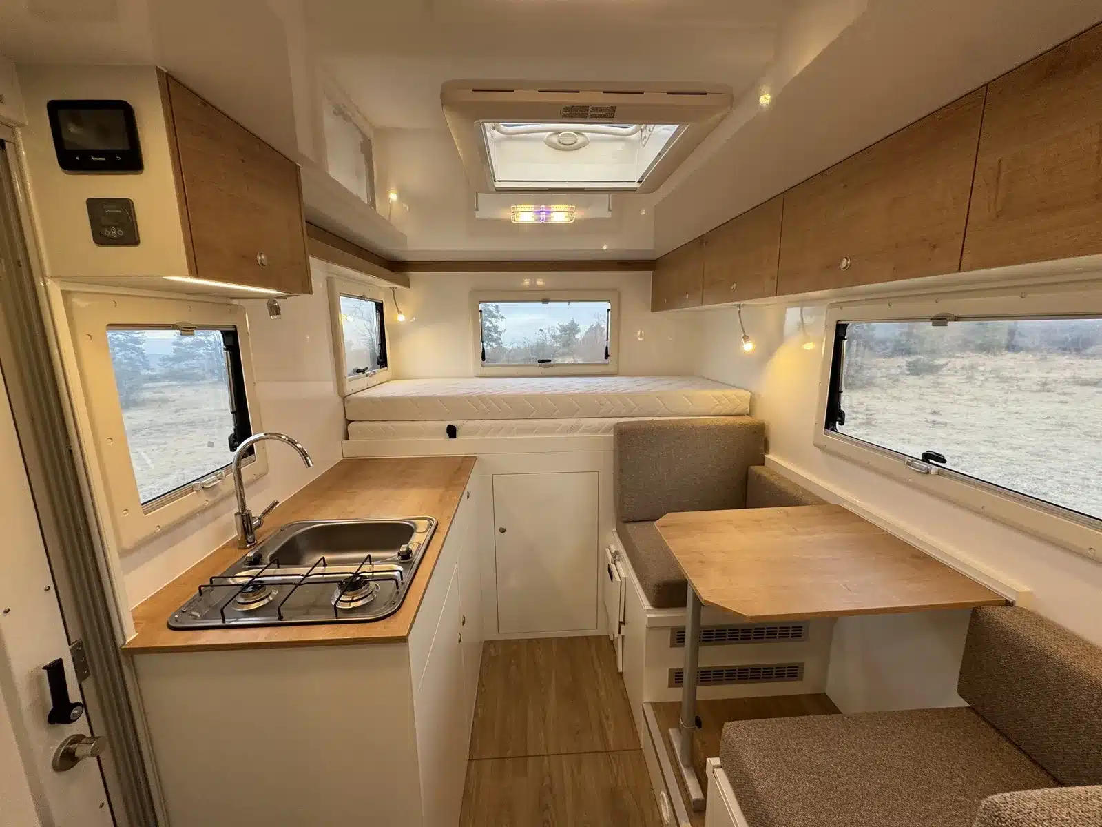 Innenraum eines kompakten Woelcke Autark runner R6 mit Küche, Sitzgruppe, Bett und Stauraum