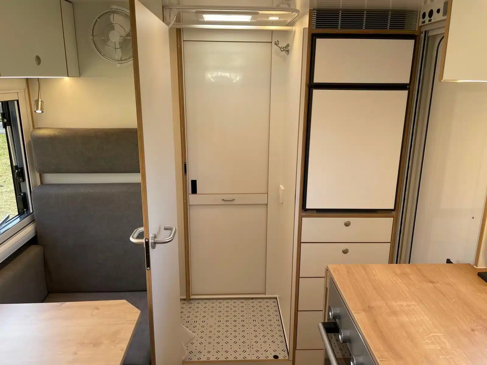 Moderner Innenraum mit Sitzgruppe, Küche, Kühlschrank und Zugang zum Raumbad des Woelcke Autark runner R6-lang, 2023-Modell
