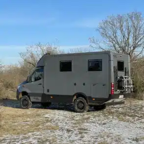 Seitenansicht eines grauen Woelcke Autark runner R7 Allradwohnmobils auf MB Sprinter 419CDI Basis im Gelände.