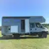 Iveco Daily 4x4 Doka mit grauem Woelcke GFK-Wohnaufbau auf einer Wiese