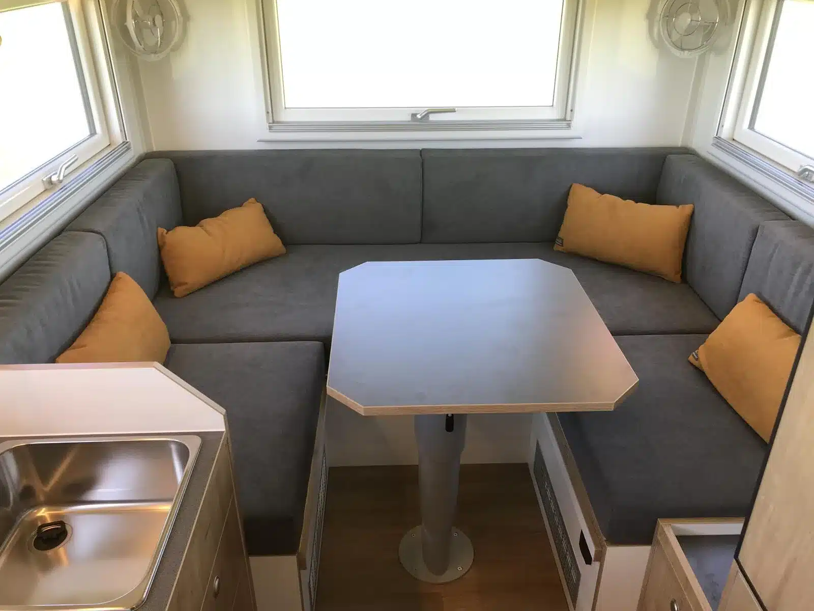Innenraum eines Iveco Daily 4x4 mit Woelcke GFK-Wohnaufbau, Sitzgruppe, Tisch und Küchenzeile
