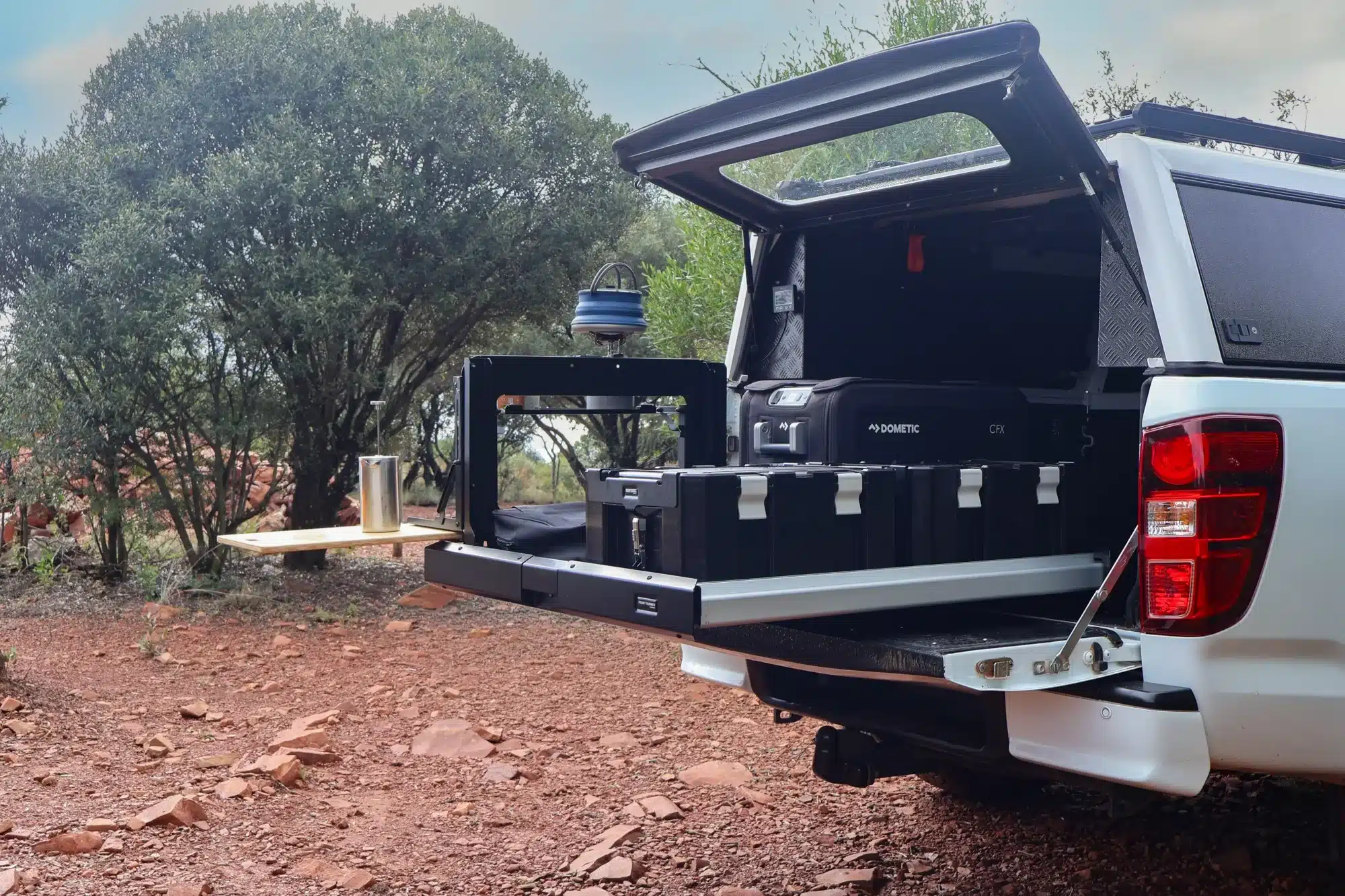 Dometic Ladeflächenauszug in einem Pick-up mit Stauboxen und Kühlbox in natürlicher Outdoor-Umgebung.