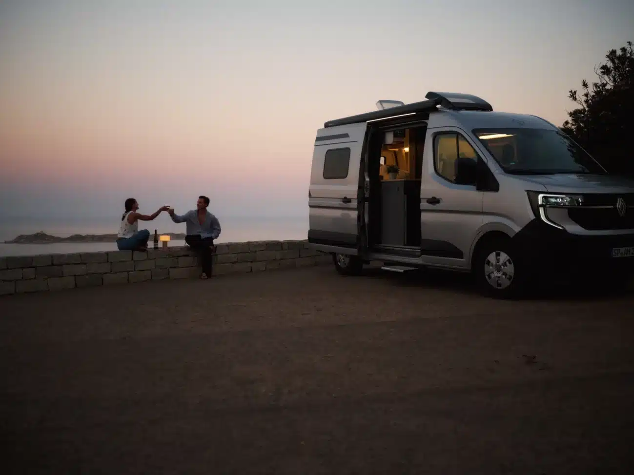 Renault Master Campervan mit offenen Türen, Sonnenuntergang und zwei Menschen am Meer