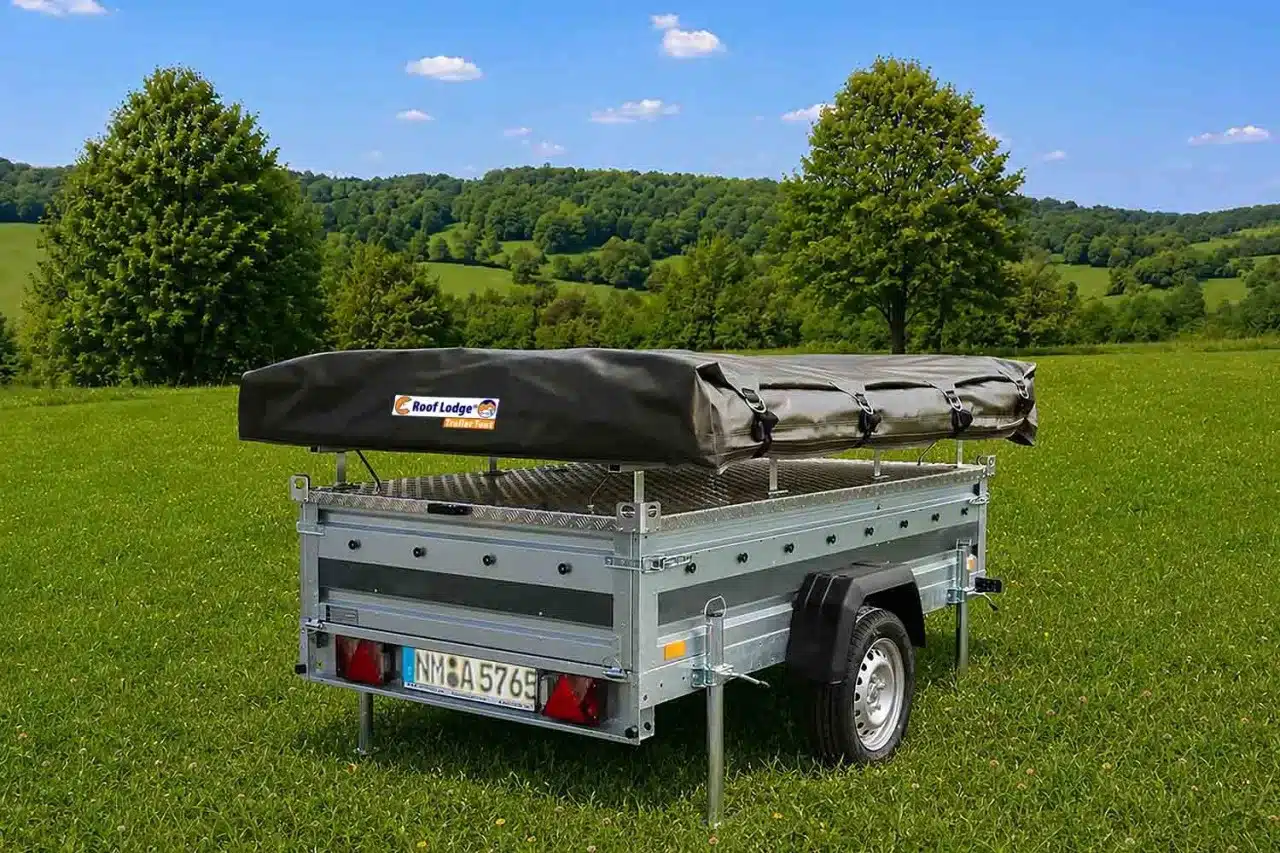 Anhänger mit geschlossenem Roof Lodge Trailer Tent auf einer Wiese vor Waldkulisse