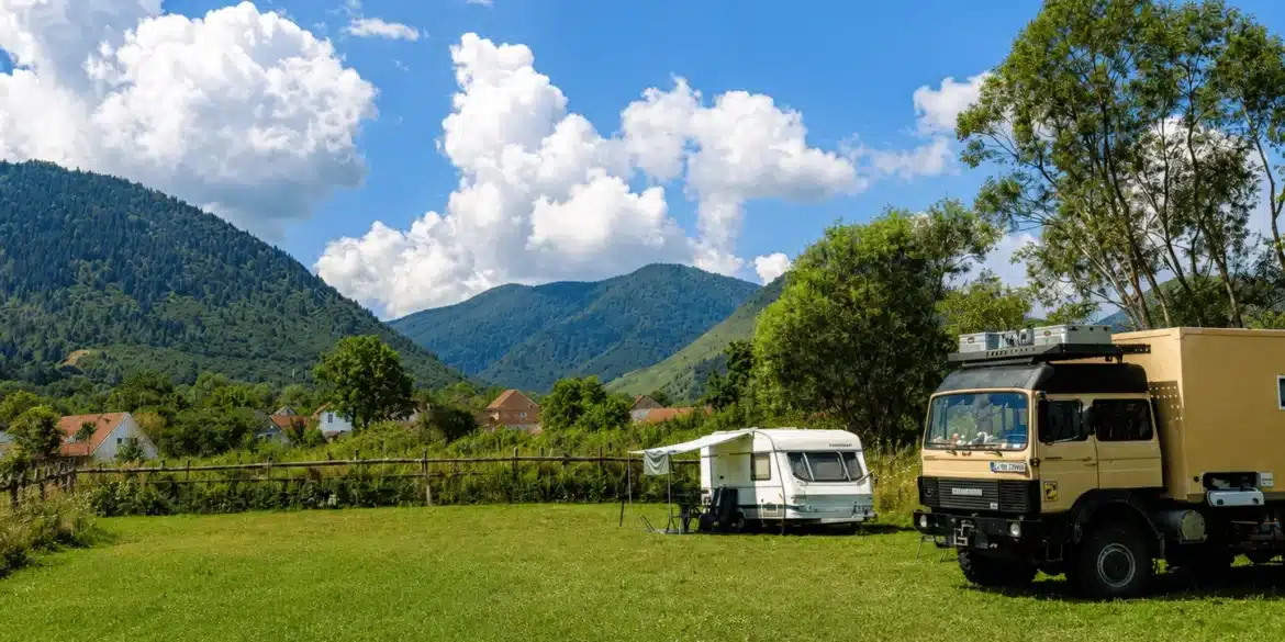 Wohnmobile und Caravan auf einem Stellplatz in Rumänien mit Bergen im Hintergrund