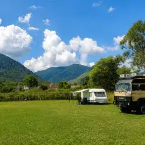 Wohnmobile und Caravan auf einem Stellplatz in Rumänien mit Bergen im Hintergrund