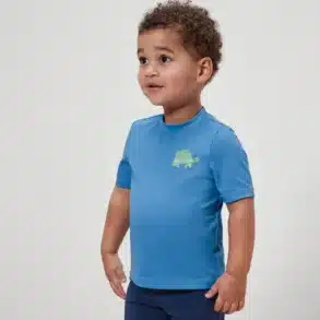 Kind in mittelblauem UV-Shirt mit Schildkröten-Motiv, kurzärmlig, blickt zur Seite, neutraler Hintergrund.