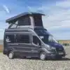 Westfalia Meridian Kastenwagen mit Aufstelldach, geparkt auf einem Kiesstrand mit Blick aufs Meer