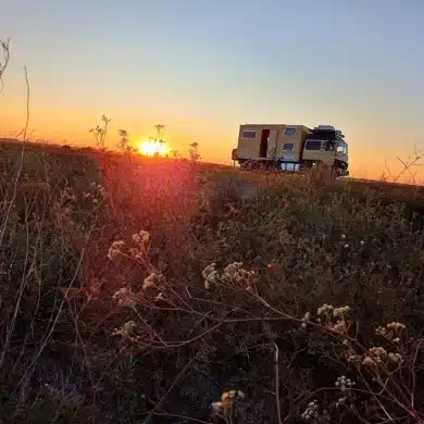 Expeditionsmobil steht beim Sonnenuntergang auf einer Wiese in Europa und vermittelt das Gefühl von Freiheit beim Wildcampen.
