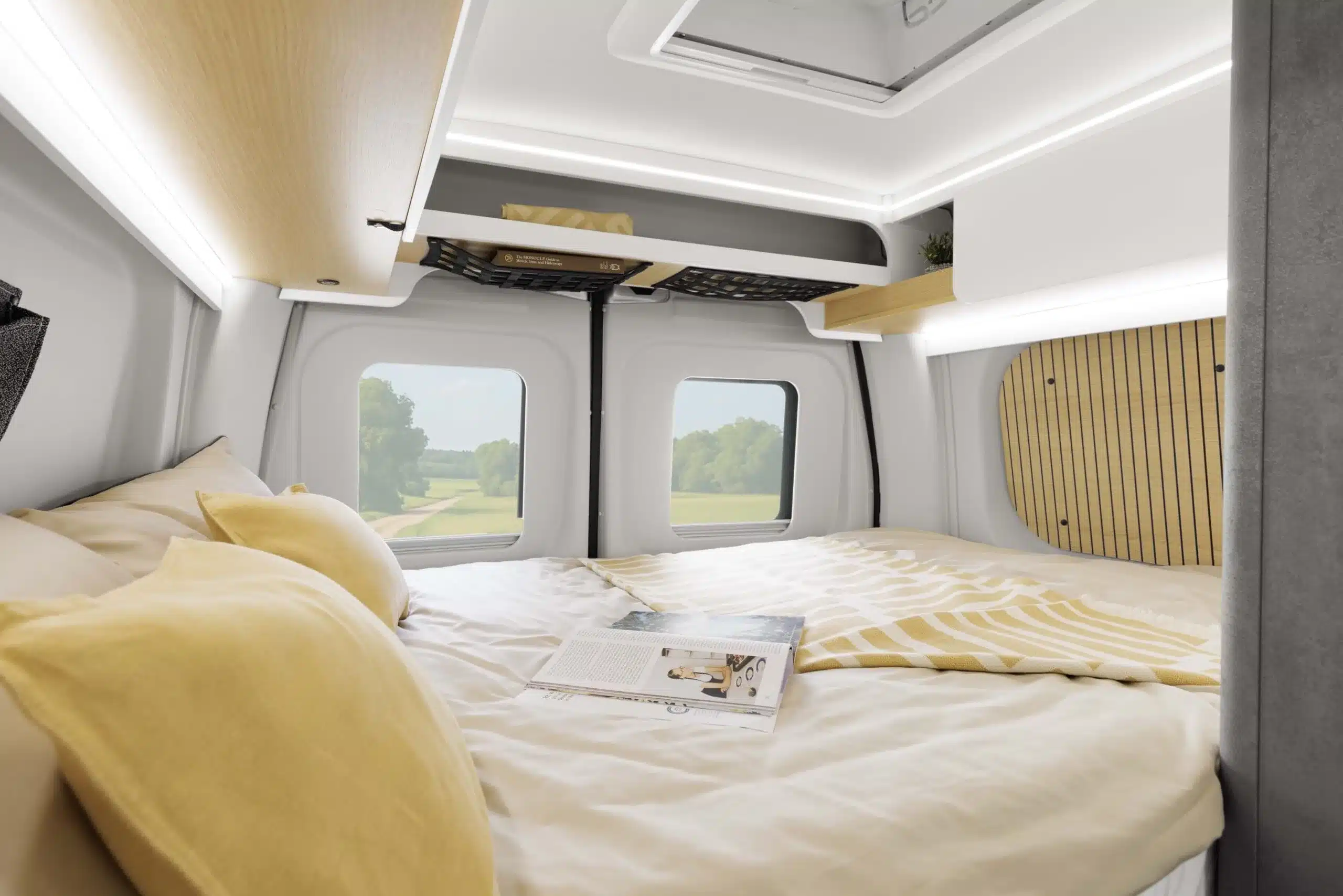 Schlafbereich im Heck des Ahorn Camp Van 560 mit Doppelbett, Stausystem und dekorativer Beleuchtung.