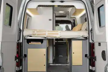 Heckansicht des Ahorn Camp Van 560 mit aufgeklapptem Doppelbett und Stauraumbereich darunter.
