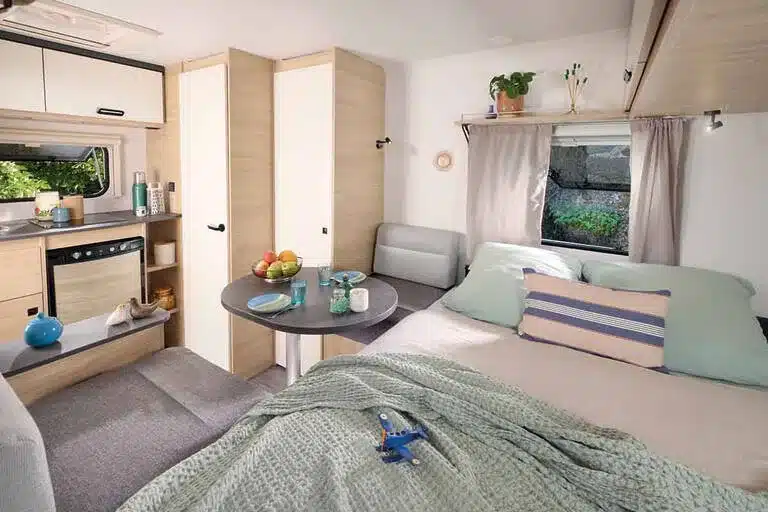 Moderner Innenraum des Caravelair ALBA 350 mit Bett, Sitzecke, Küche und Stauraum