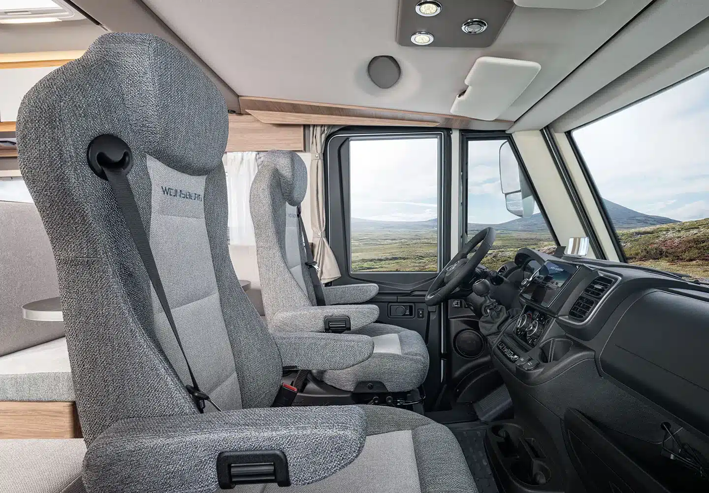 Blick auf die Fahrerkabine und Sitzgruppe des WEINSBERG CaraCore mit großem Fenster und heller Innenausstattung