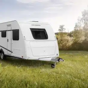 WEINSBERG CaraLife Caravan steht auf einer grünen Wiese bei Sonnenschein.