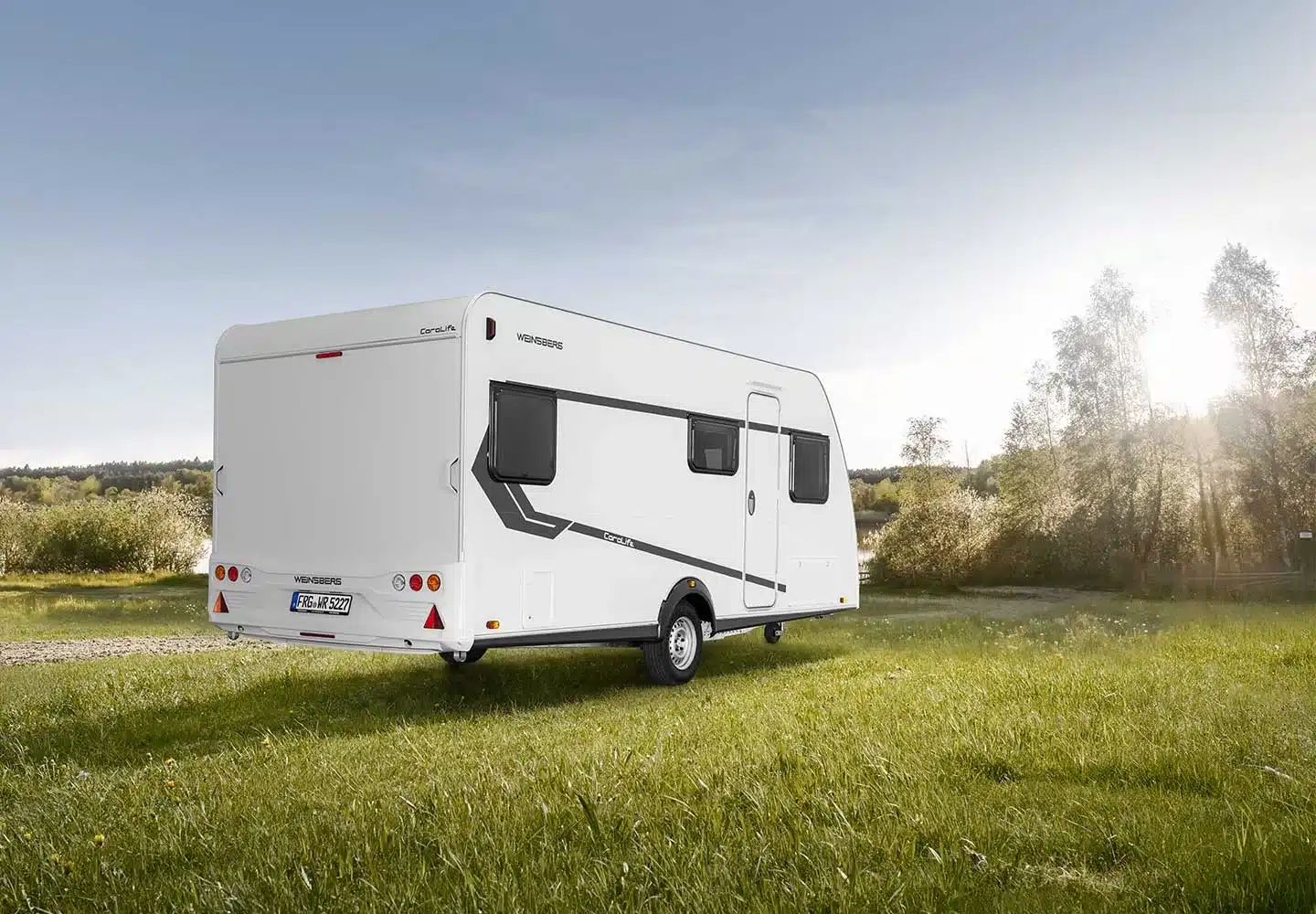 WEINSBERG CaraLife Caravan von außen auf einer grünen Wiese bei Sonnenschein
