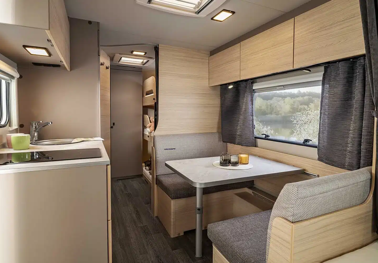 Innenansicht des WEINSBERG CaraLife Caravans mit moderner Sitzgruppe, Küchenzeile und Fenster